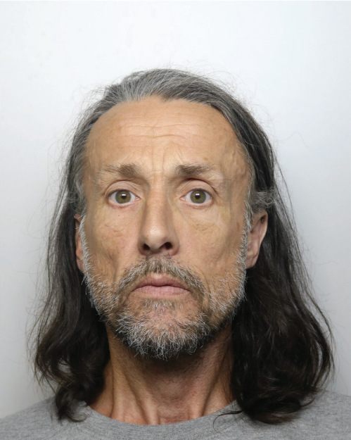 Mugshot of a man with long graying brown hair and a beard.