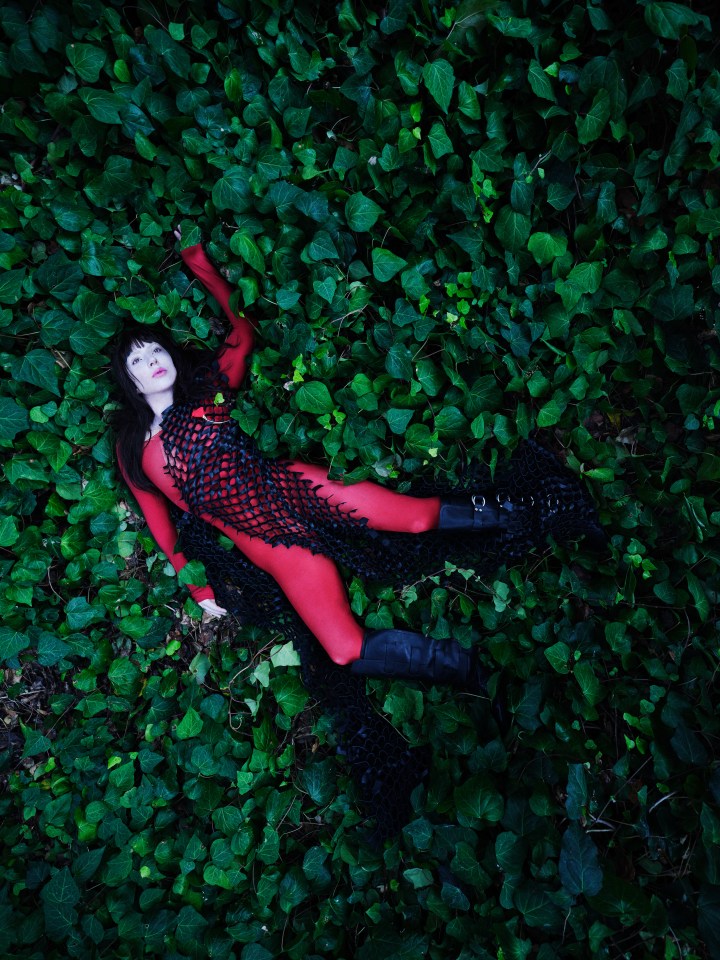 Woman in red bodysuit lying on ivy.