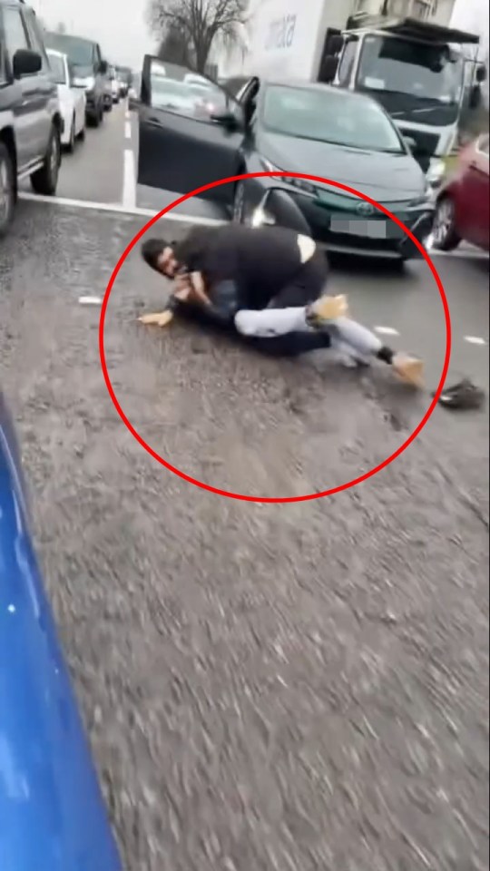 Two men wrestling on a road.