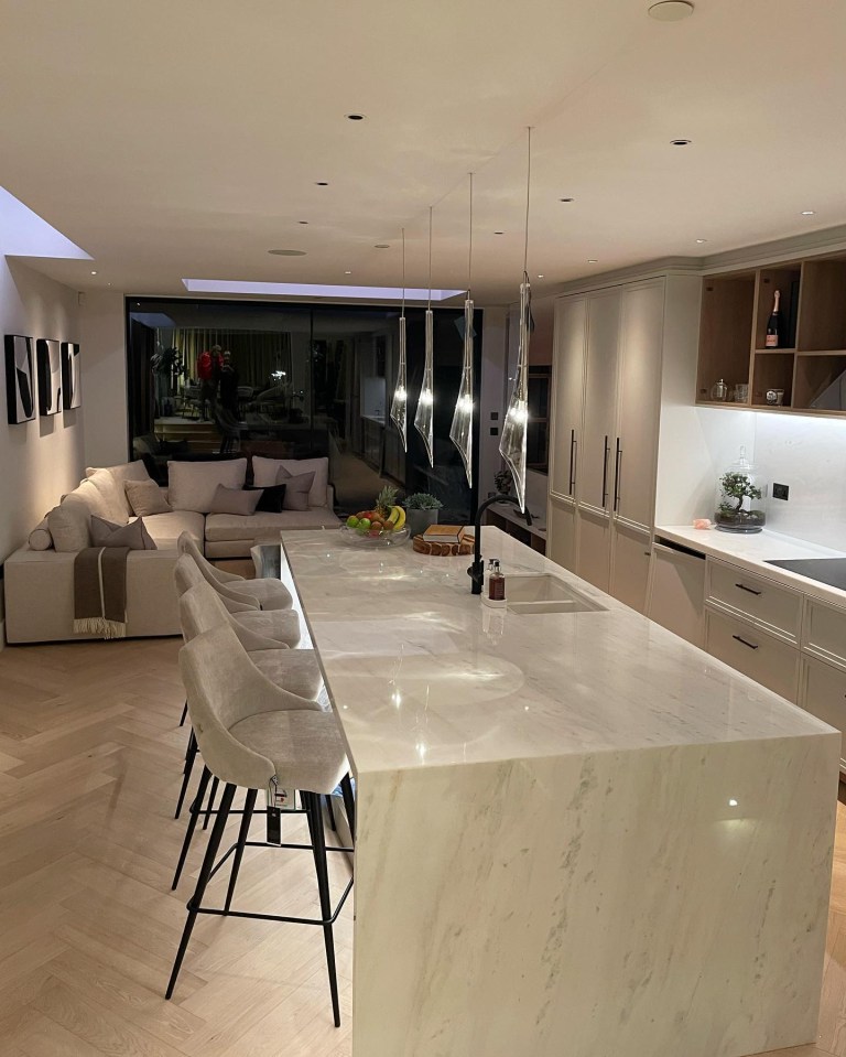 Renovated kitchen and living area with marble island and bar stools.