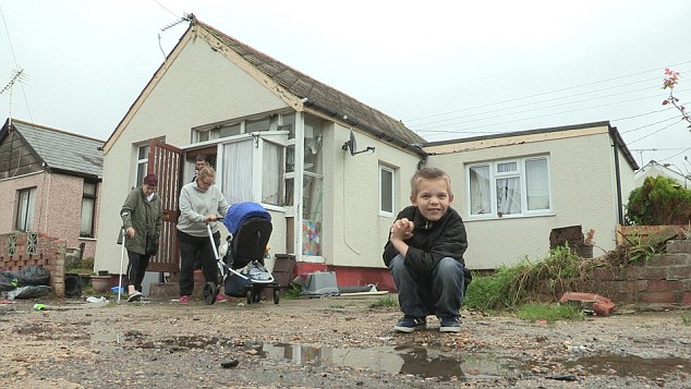 A boy sits in front of his family's home in Jaywick, Essex.