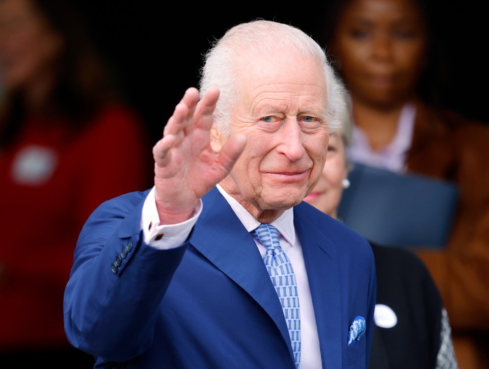 King Charles III waves at the opening of a Coronation Food Hub.