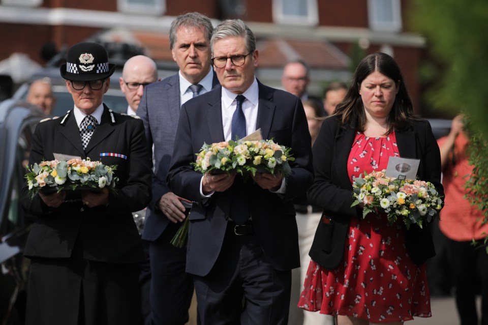 Prime Minister Keir Starmer and others carrying floral tributes.