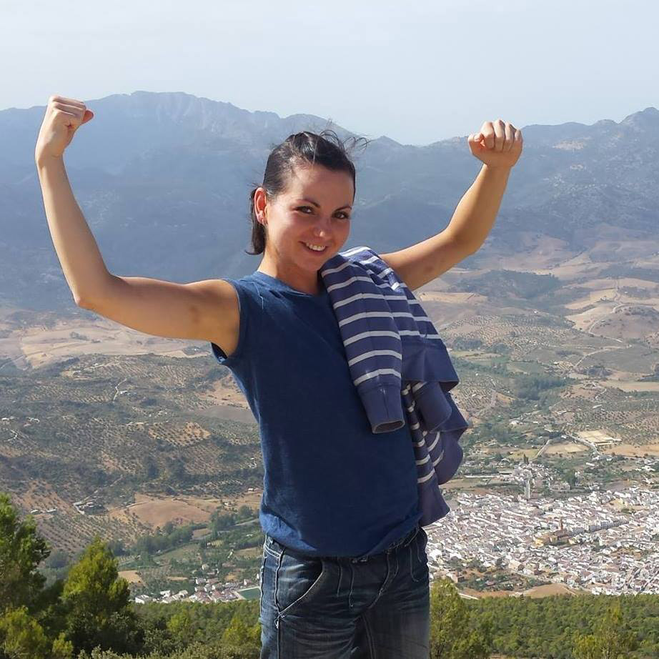 Woman with arms raised overlooking a valley.