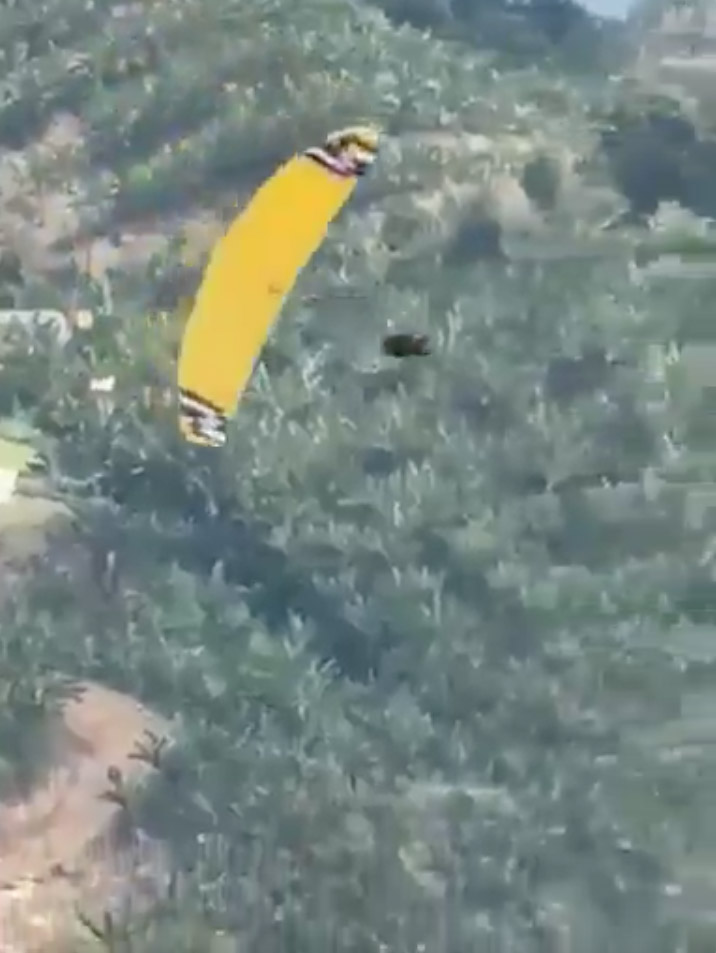 Video still of a skydiver falling from a paraglider.