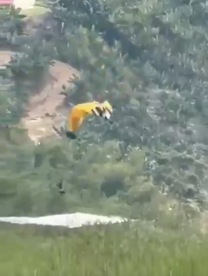 Video still of a skydiver falling from a harness.