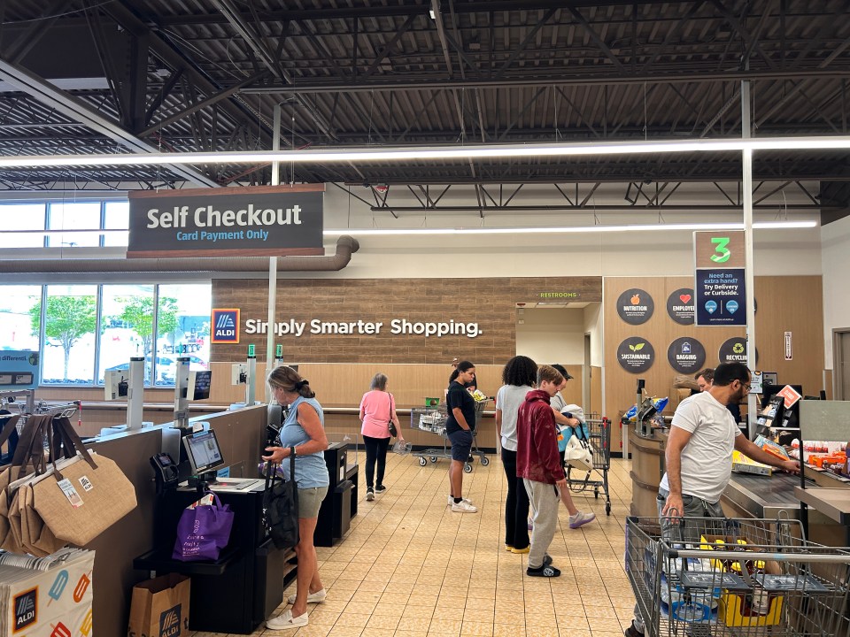 Aldi grocery store self-checkout lanes with customers.