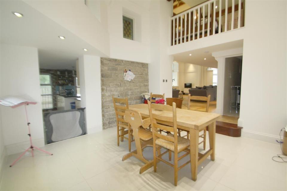 Dining area with wooden table and chairs, kitchen visible in background.