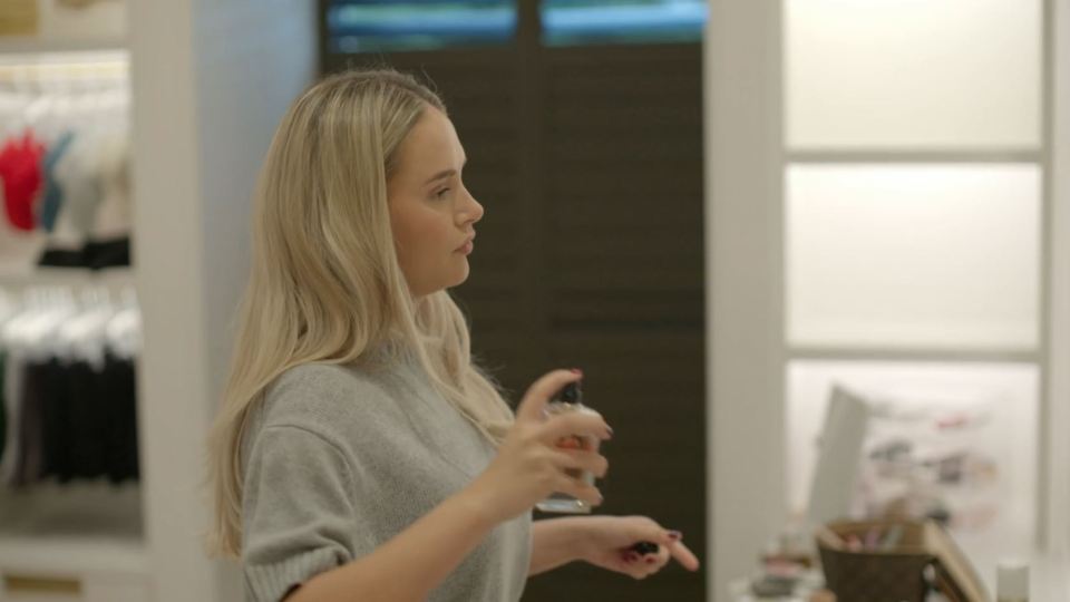 Woman spraying perfume in a store.