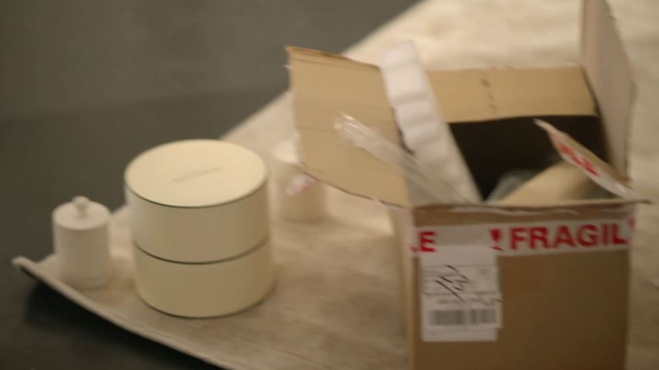 A partially opened box labeled "Fragile" containing several items, including two cylindrical containers.