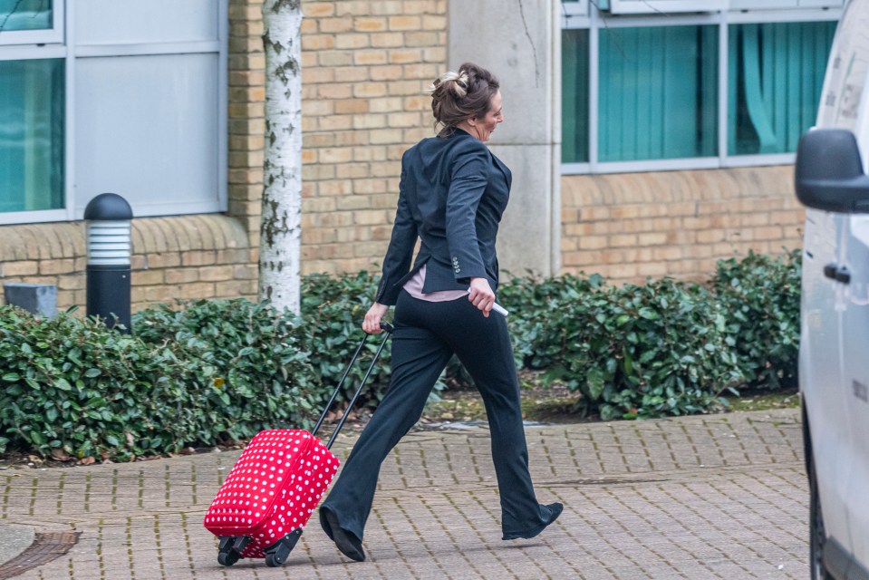 Woman leaving Bournemouth Crown Court with a red polka dot suitcase.