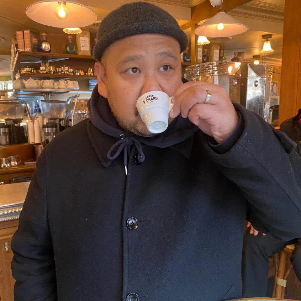 Man in a dark coat drinking espresso in a cafe.