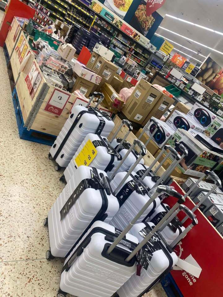 Supermarket aisle with suitcases and other discounted goods.