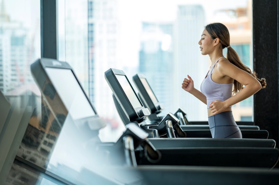 Young woman jogging on a treadmill in a gym.