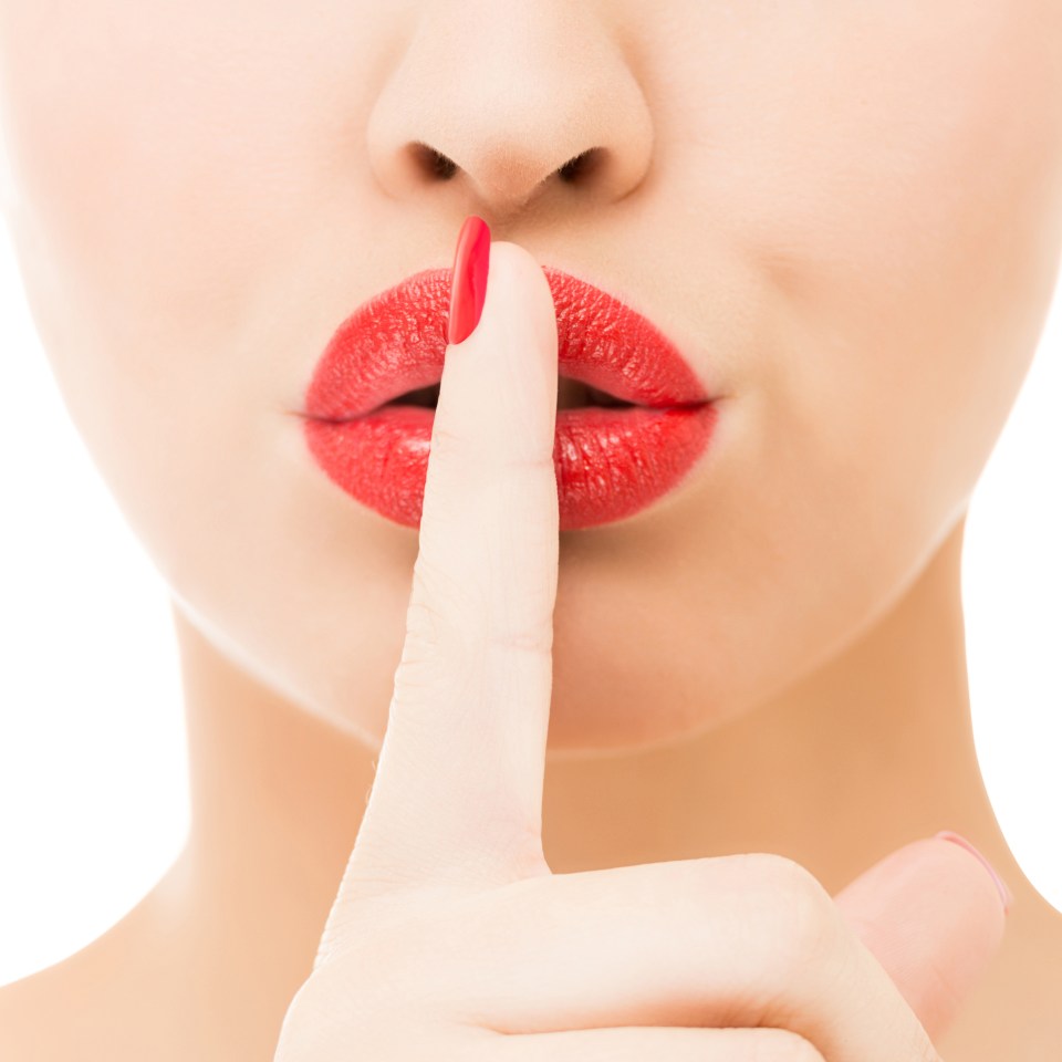 Woman's finger over lips, signaling silence.