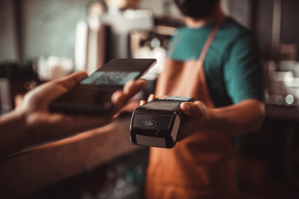 Contactless payment with smartphone at a cafe.