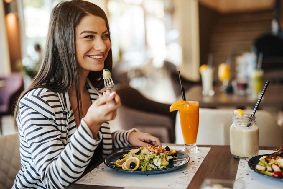 Smiling woman enjoying a restaurant lunch.