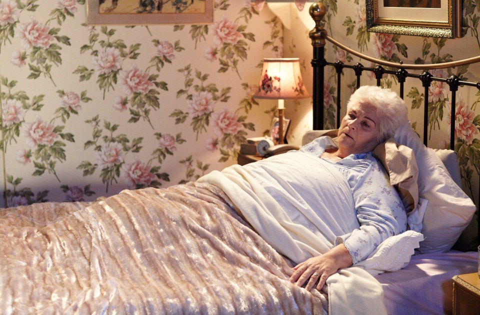 Elderly woman lying in bed looking unwell.