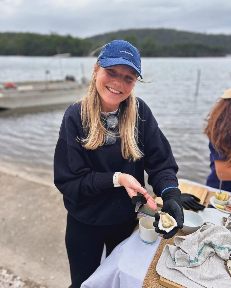 Woman shucking an oyster outdoors.