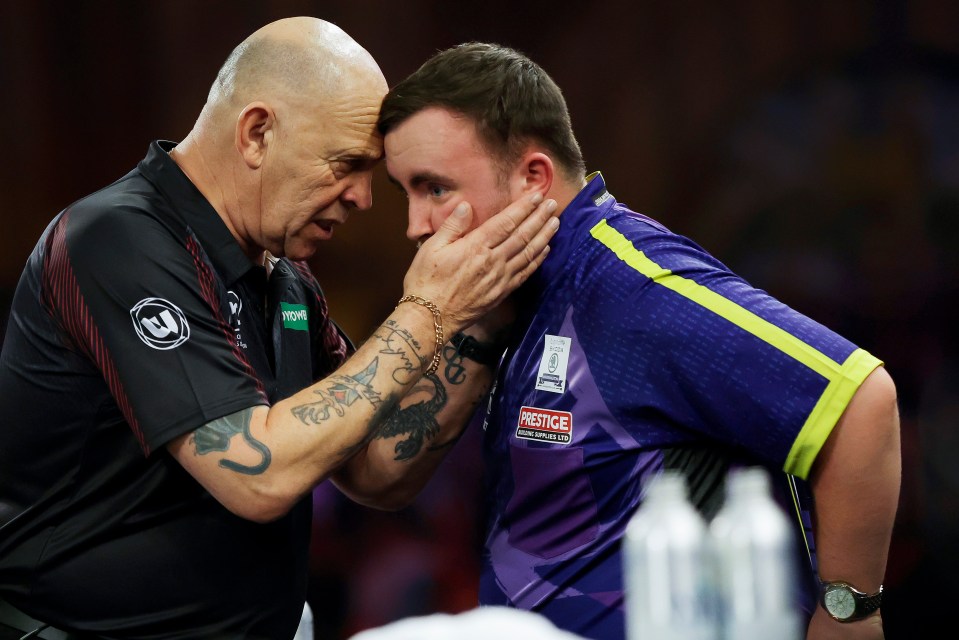 Referee Russ Bray speaks with Luke Littler after a darts match.