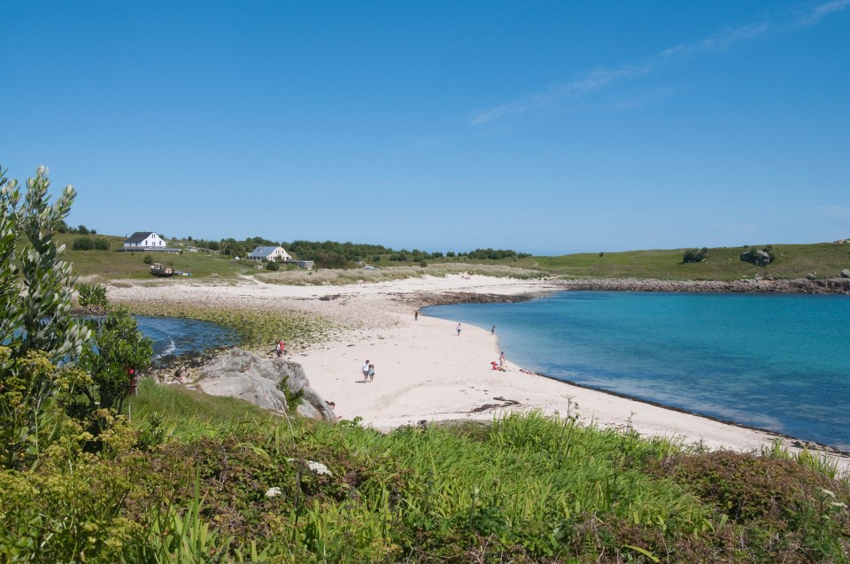 Beach scene with people on a sandy beach and turquoise water.