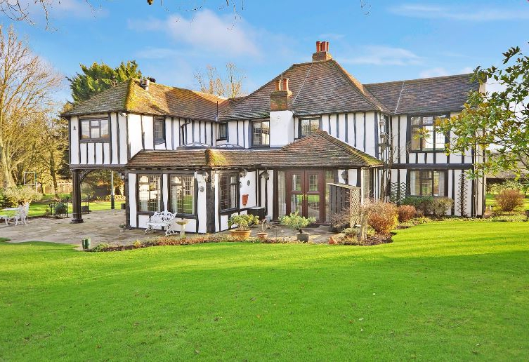 Large black and white Tudor-style house with a well-manicured lawn.