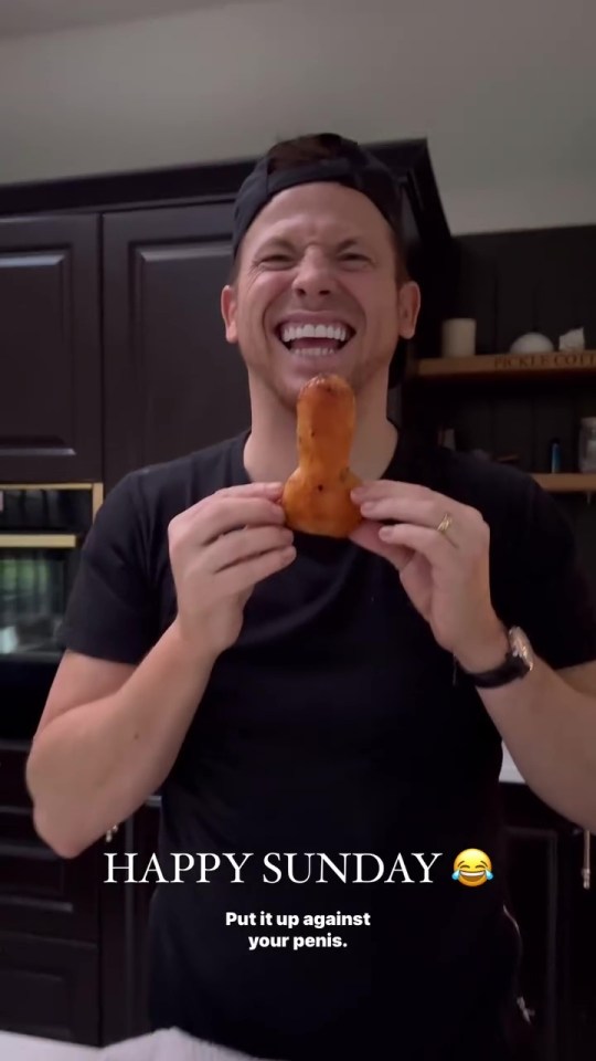 Man holding up a phallic-shaped roast potato and laughing.