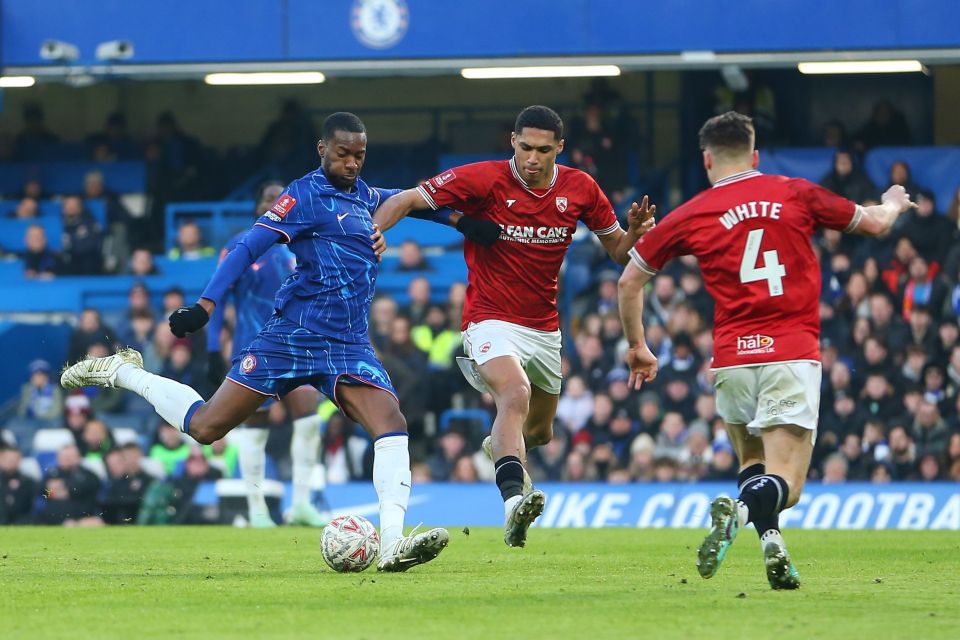 Chelsea player kicking the ball during a soccer match.