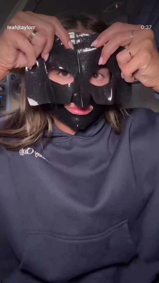 Woman applying a black sheet face mask.