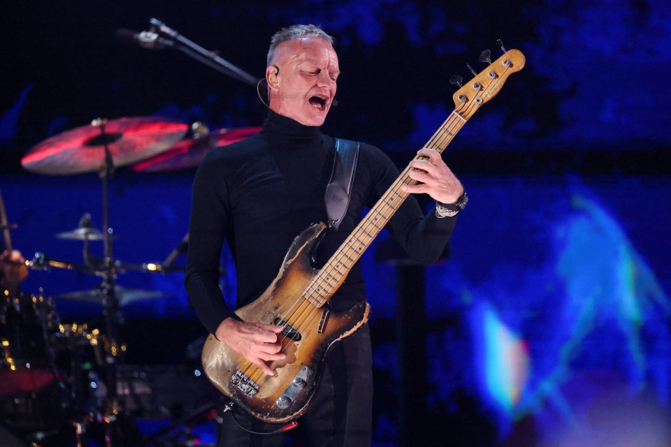 Sting playing bass guitar at a concert.