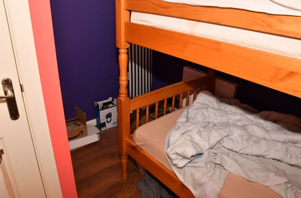 A messy bedroom with a bunk bed, boxes, and purple walls.