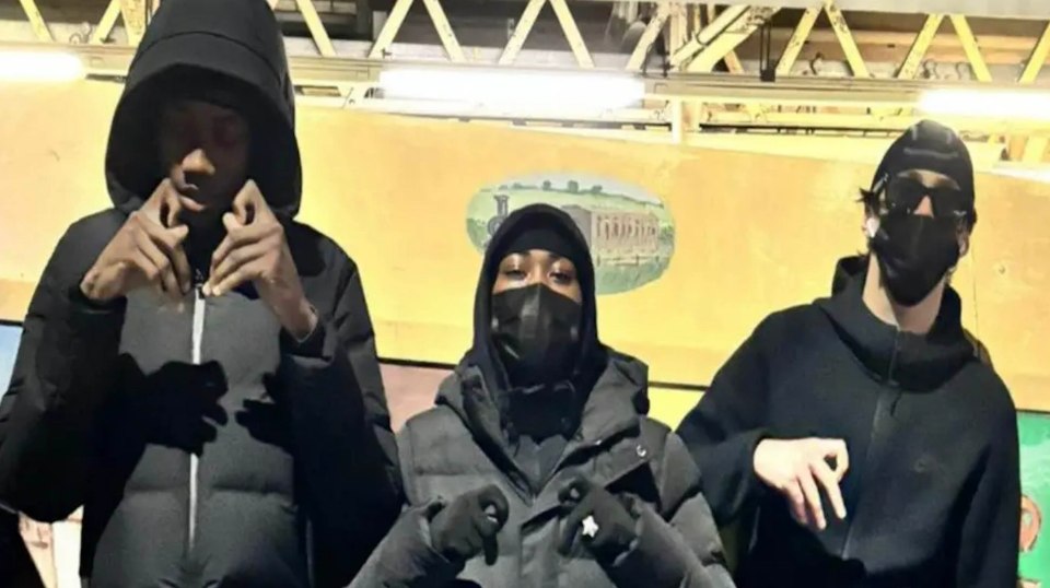 Three people in dark clothing and masks.