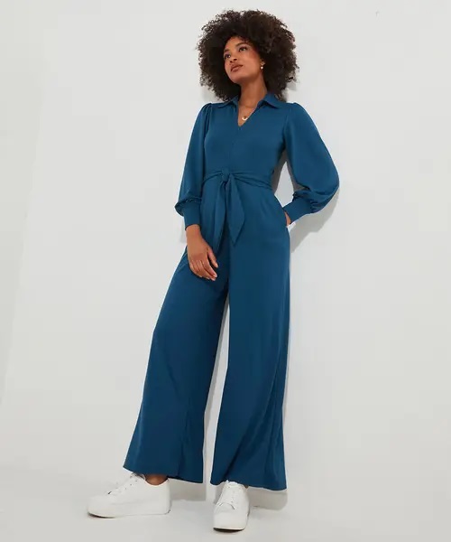 Woman in teal wide-leg jumpsuit with self-tie belt.