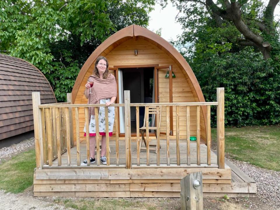 Woman enjoying wine on the deck of a glamping pod.