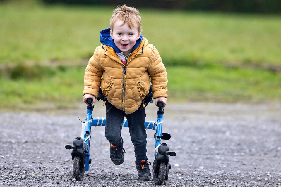 A young boy with cerebral palsy runs with a walker to support his parents' charity run.