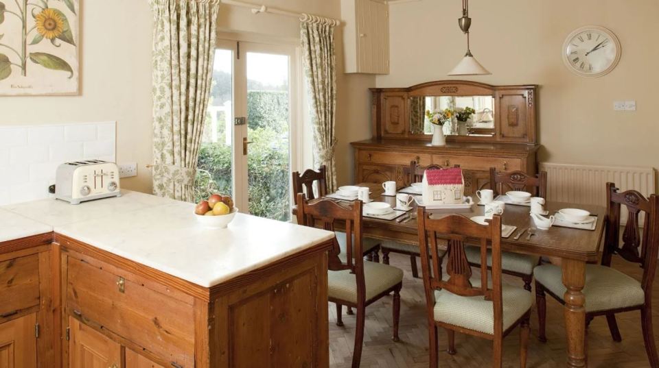 Kitchen and dining area in a cottage, featuring wooden furniture and garden views.