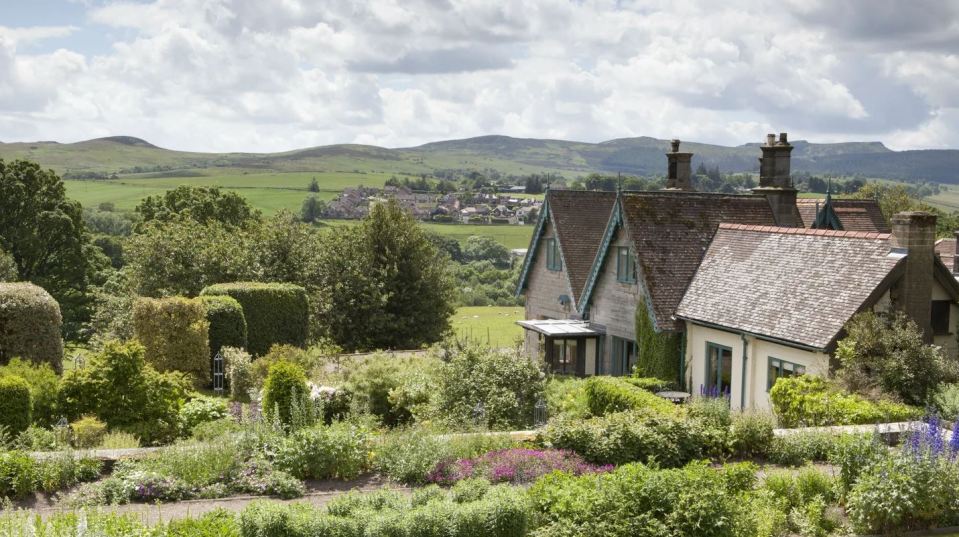 Cragside Garden Cottage and gardens overlooking a valley and village.