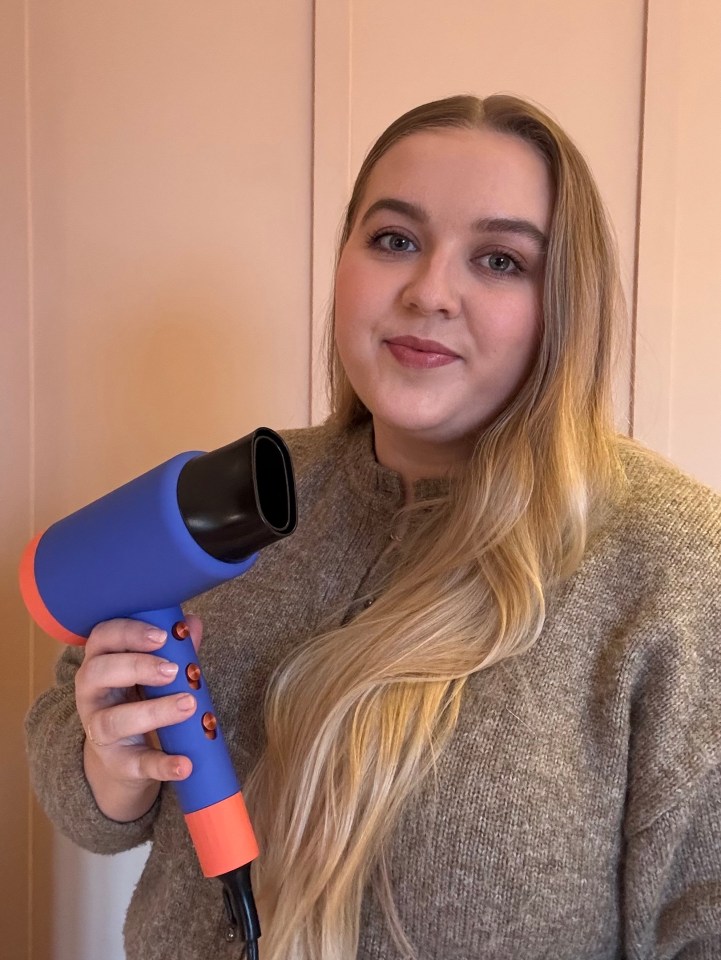 Woman holding a blue and orange hair dryer.