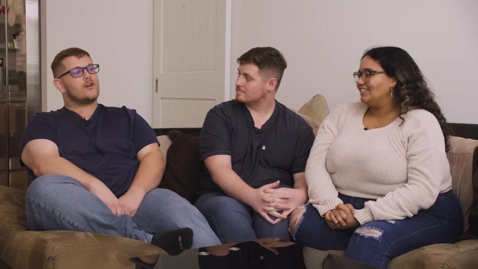 A throuple sits on a couch and talks.