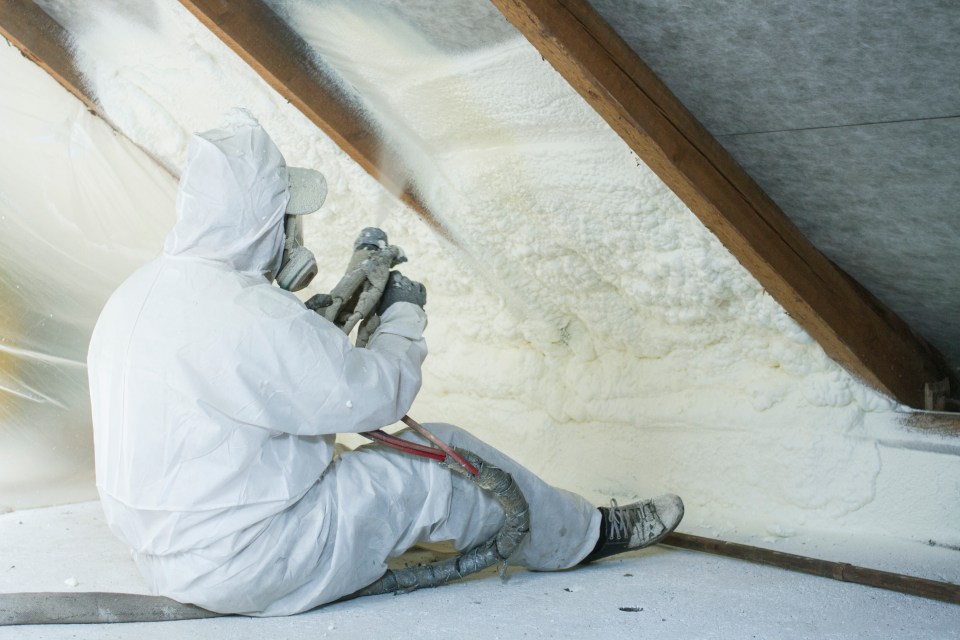 Technician spraying foam insulation in an attic.