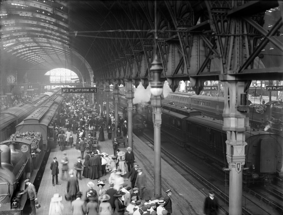 Crowded train platform with passengers boarding and departing trains.