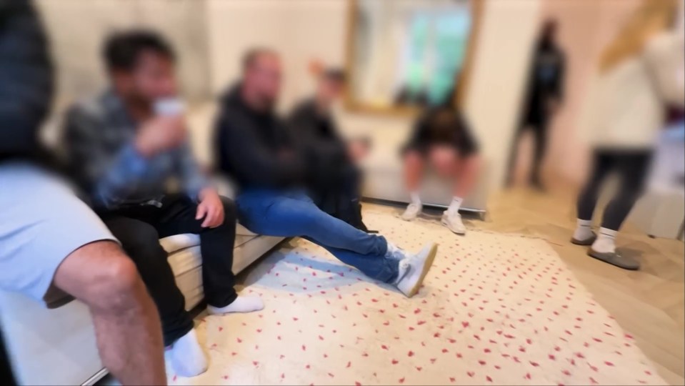 Blurry photo of several people sitting on a couch and standing in a room.