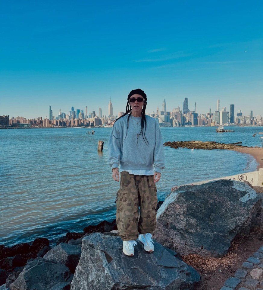 Woman standing on rocks overlooking a city skyline.