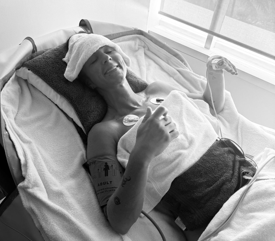 Black and white photo of a woman in a hospital bed receiving medical treatment.