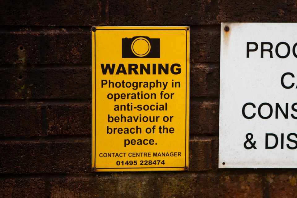 Warning sign about photography in operation for anti-social behavior or breach of the peace.