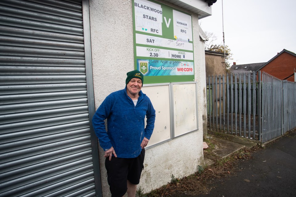 Man standing by a rugby club sign.