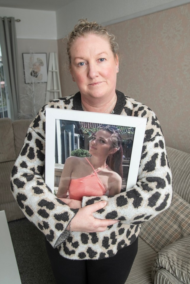 A woman holds a framed photo of her deceased daughter.