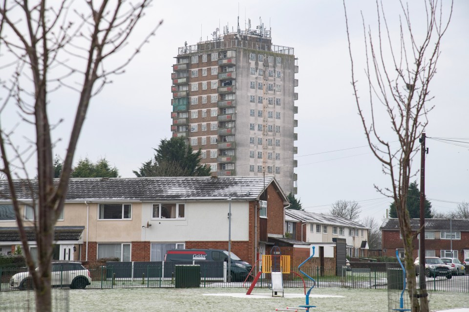 A high-rise apartment building in a residential area with a light dusting of snow on the ground.