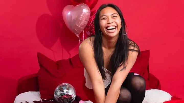 Woman smiling with heart-shaped balloons.