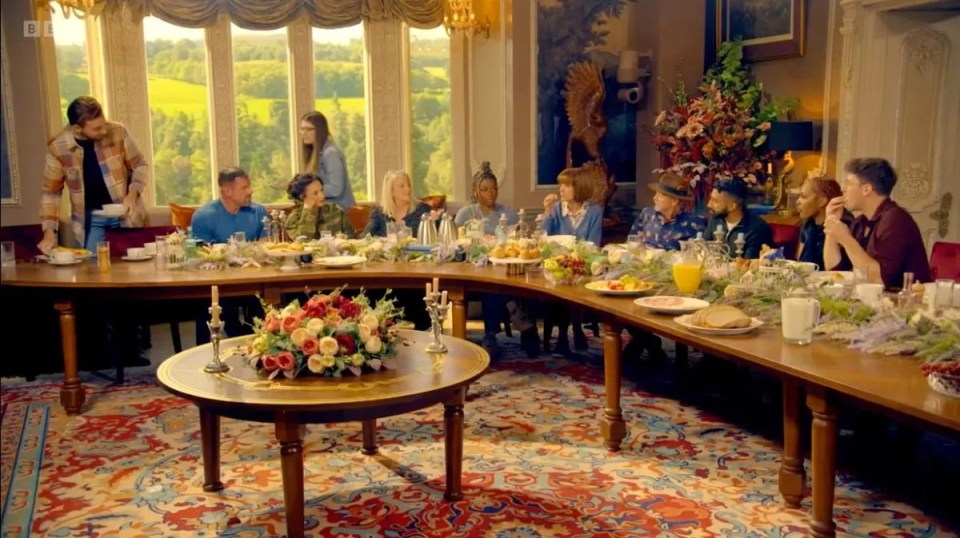 A group of people enjoying breakfast at a long table in a grand room.